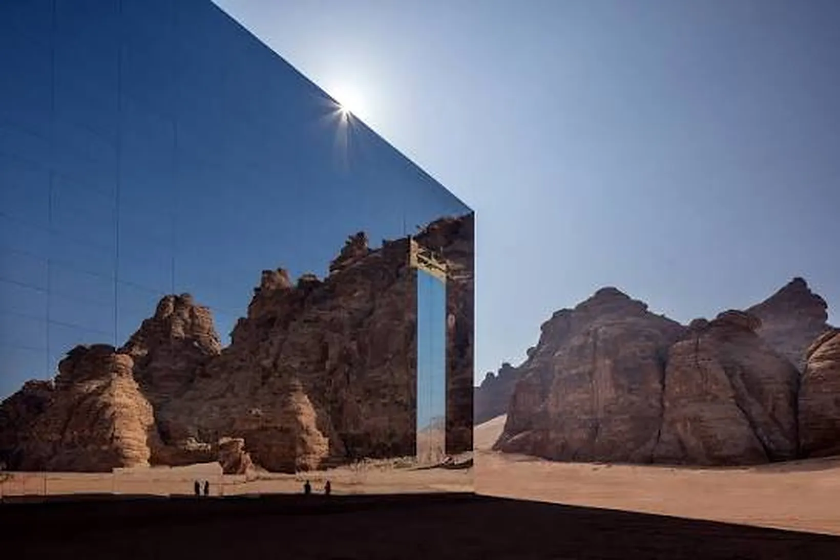 The mirrored façade of Maraya concert hall reflecting the sun and the sandstone canyon walls around it